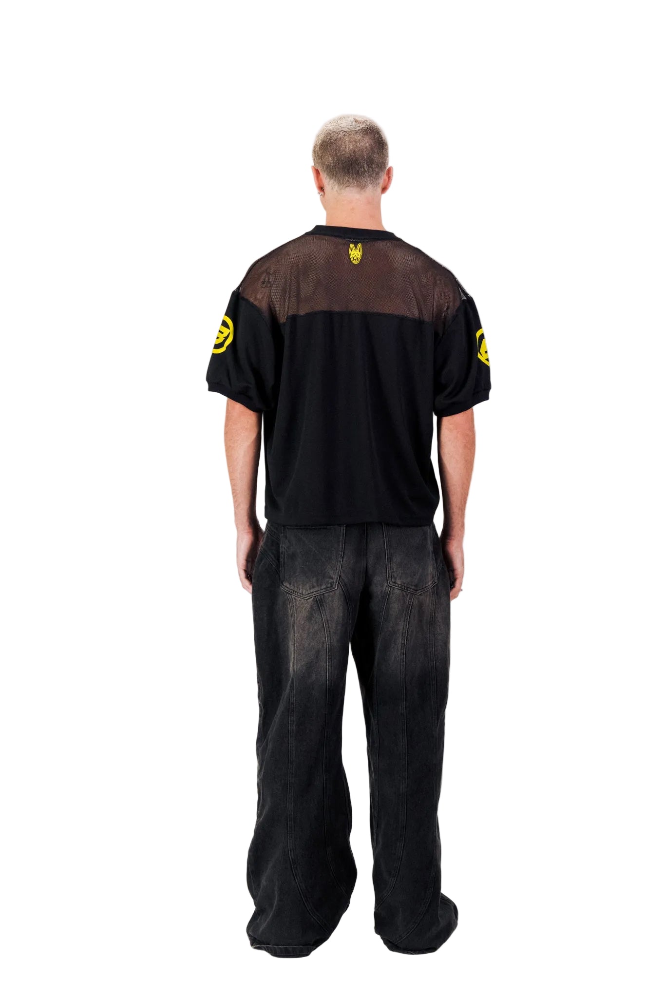 Person wearing a black outfit with yellow accents on a white background